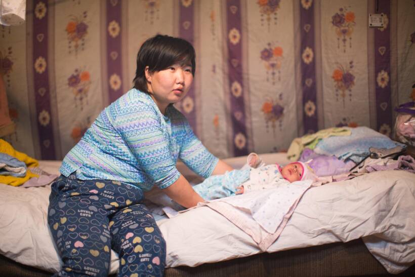 Mongolialainen nainen hoitaa vauvaa jurtassa.