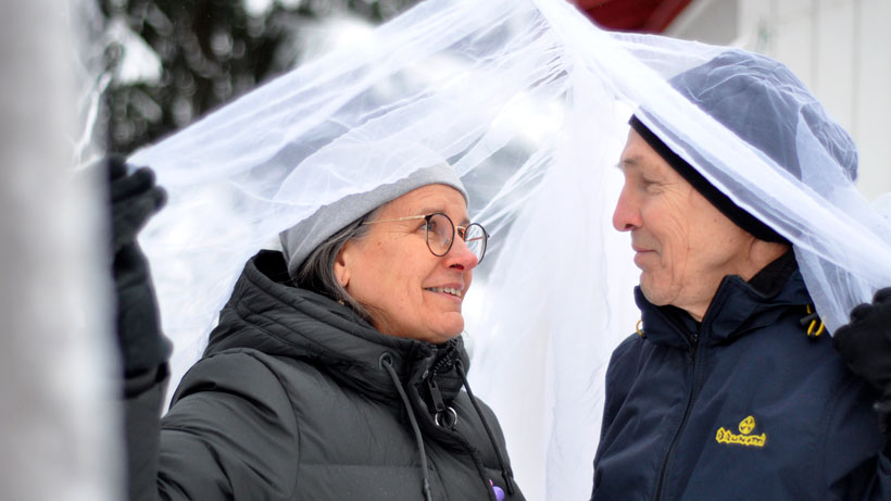 a-couple-smiling-at-each-other-outside-in-snow-under-a-mosquito-net_photo-Saija-Tiilikainen