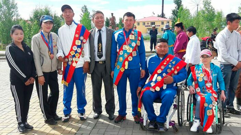 Mongolian people looking at camera, two of them are sitting in a wheelchair.