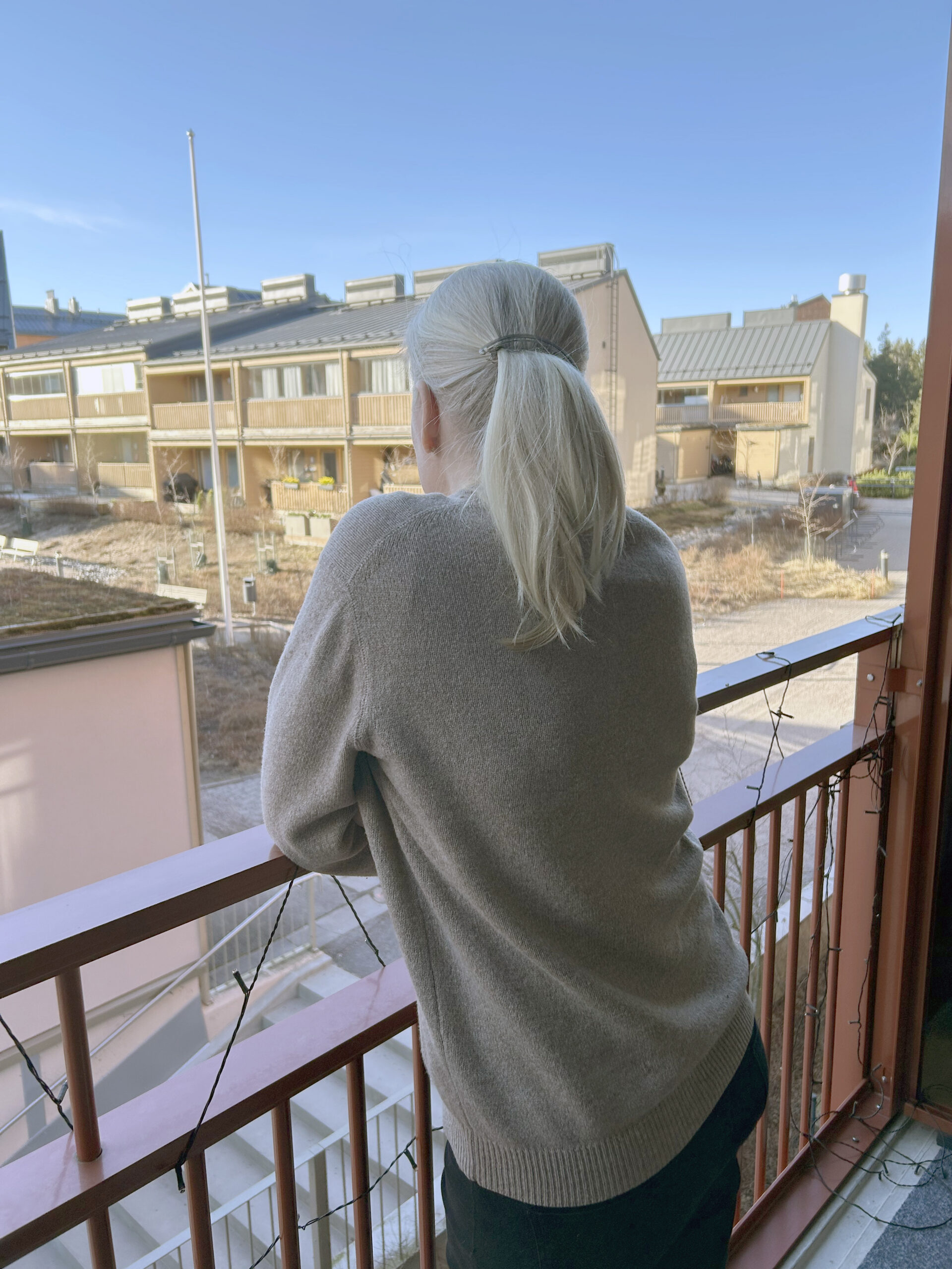 A woman looking out from balcony, no face showing.