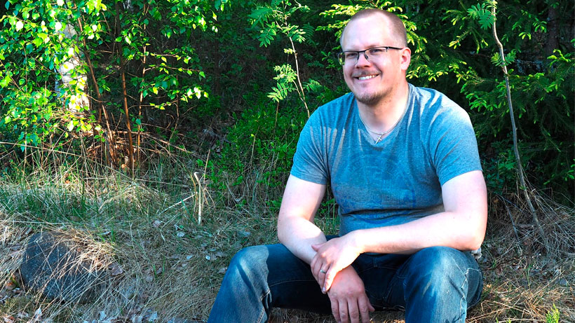Happy man sitting outside in the nature, smiling.