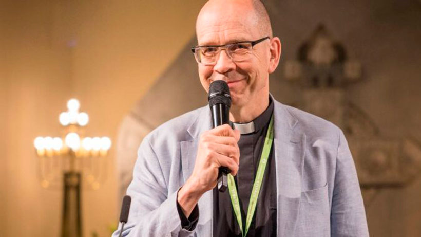 A man smiling and holding a microphone.
